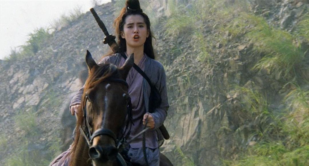 一名背着长剑的女子骑在山路上的马背上