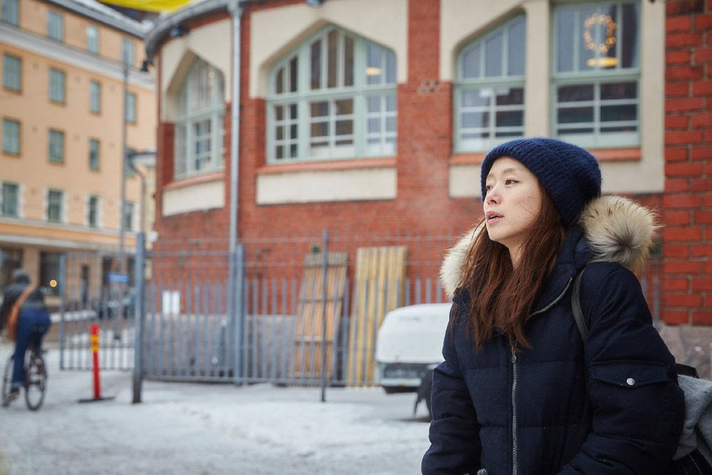 穿深色羽绒服的女人站在异国街头回望