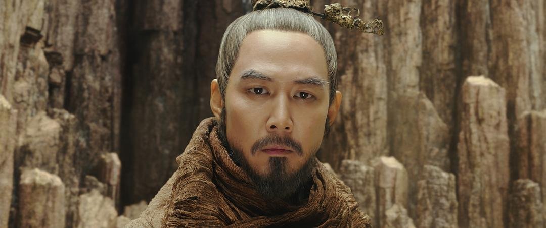 束发蓄须的男子站在高耸岩柱前直视前方