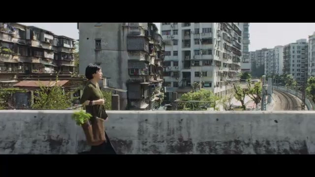 短发女子沿高楼与轨道旁的高架步道行走