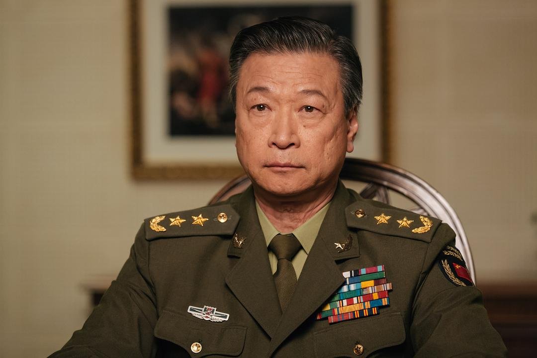 一名穿军装的男子坐在室内面对镜头