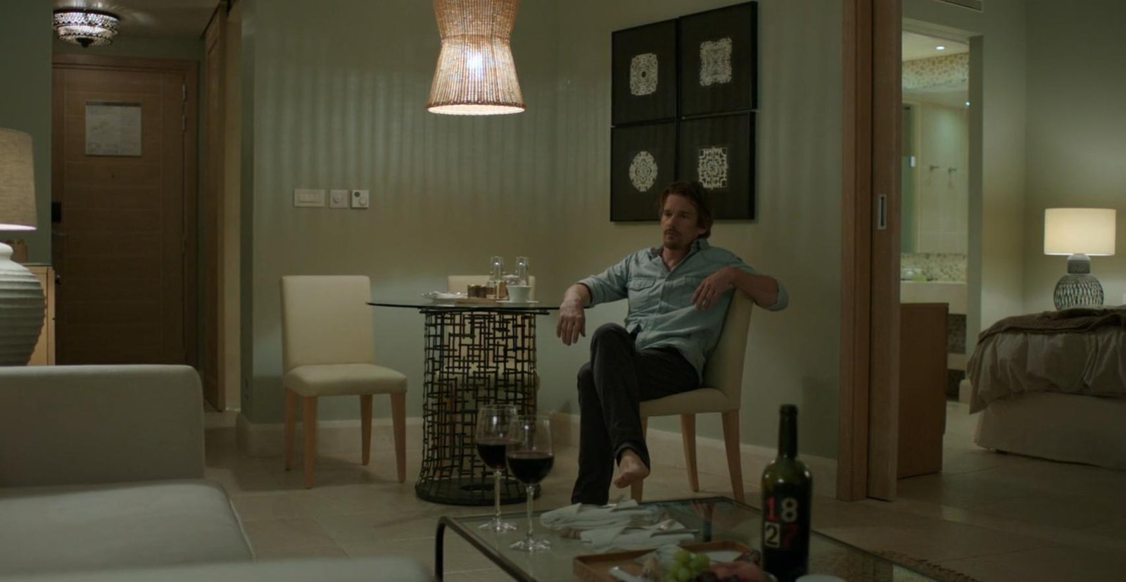 一名男子独自坐在酒店房间的椅子上
