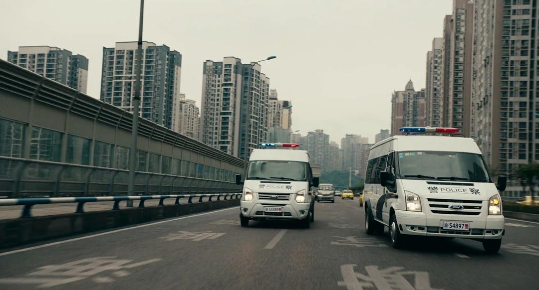 两辆亮着警灯的警用车辆驶过城市道路