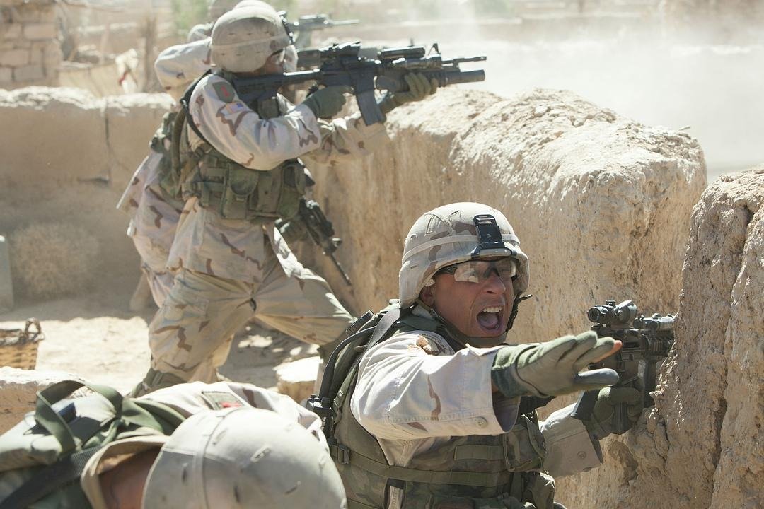 两名士兵在土墙后持枪还击，前方一名士兵伸手示意