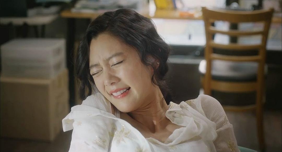 穿白色上衣的女子靠在椅背上闭眼微笑