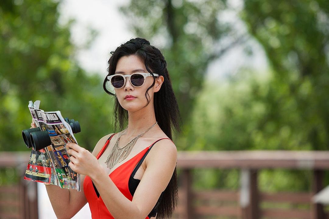 戴墨镜的女子在户外拿着杂志和黑色物品