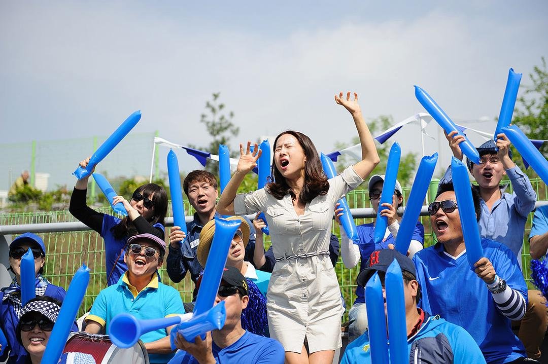 一名女子站在挥舞蓝色充气棒的人群中举手呼喊