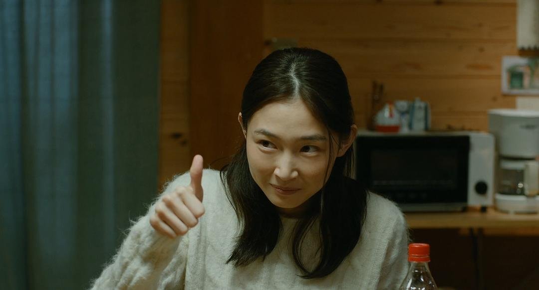 长发女子坐在餐桌旁抬起手