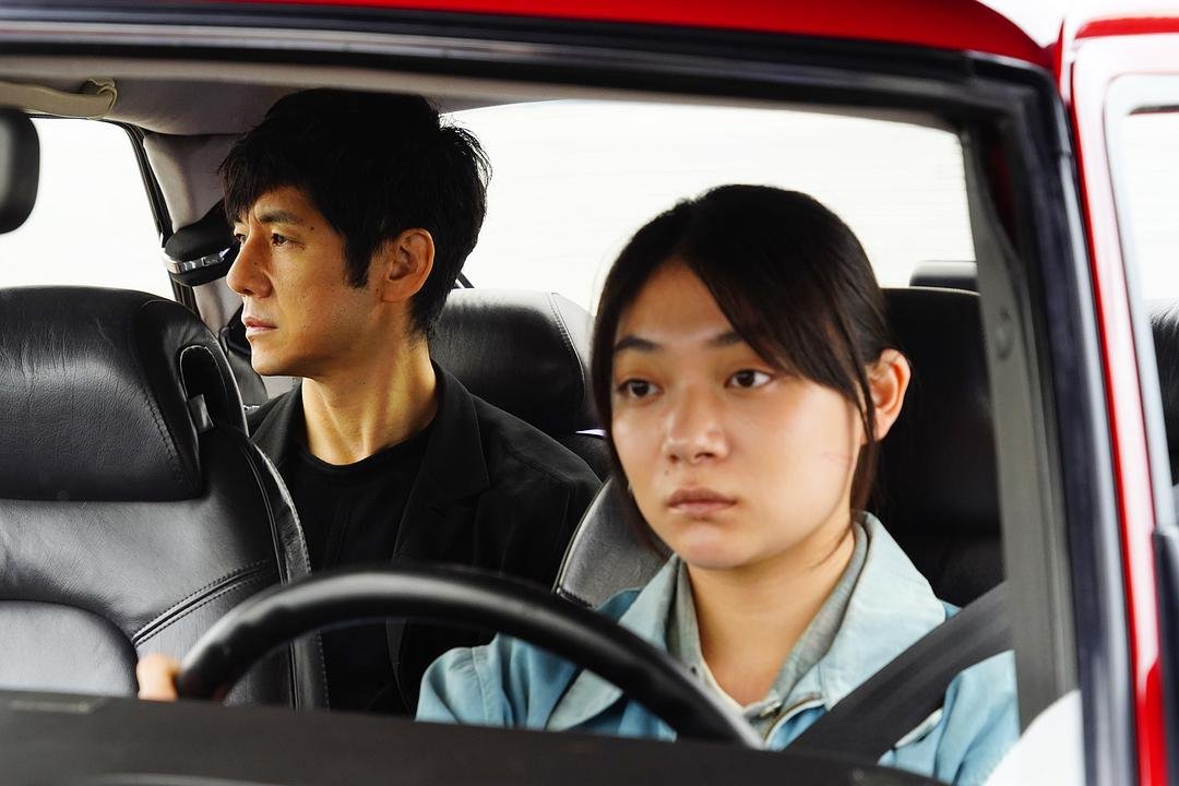 一名女子驾驶红色汽车，后排男子望向车外