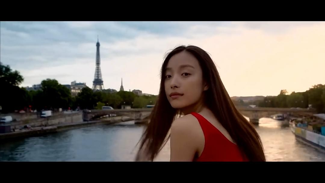 红衣女子站在塞纳河边回头，远处可见埃菲尔铁塔
