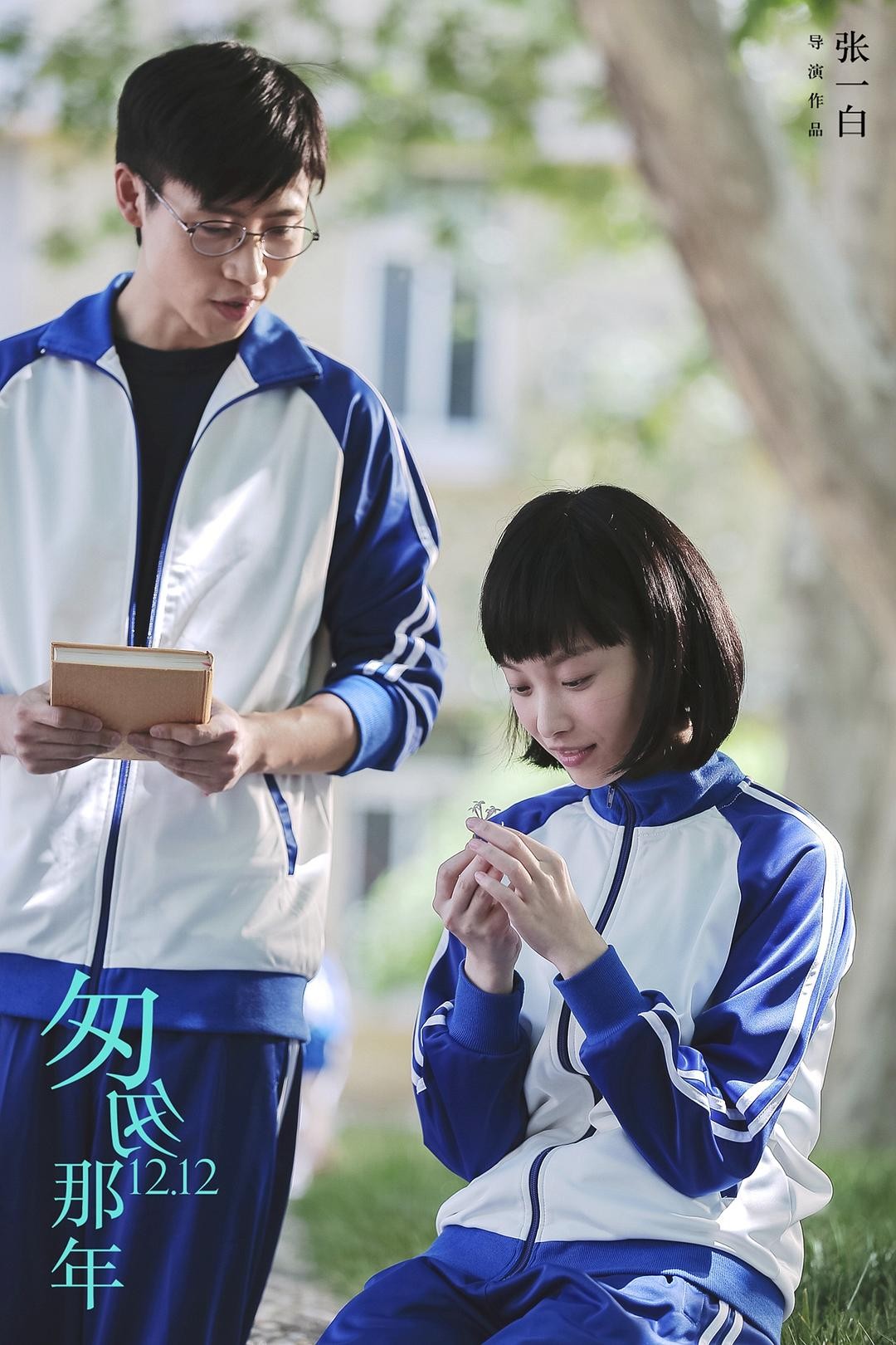 戴眼镜的男生拿着书站在手捧花枝的短发女生身旁
