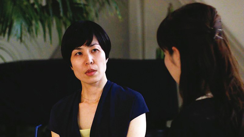 短发女子坐在室内与长发女子面对面交谈
