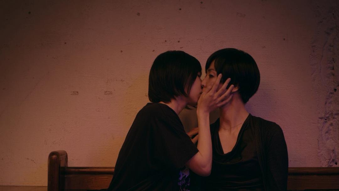 两名短发女子坐在长椅上接吻