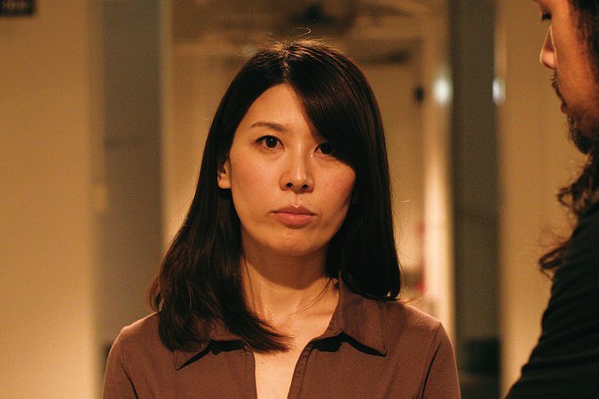 长发女子站在室内与一名男子交谈
