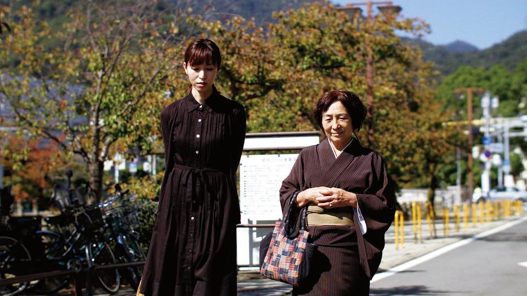穿黑色连衣裙的年轻女子与和服老妇走在街边