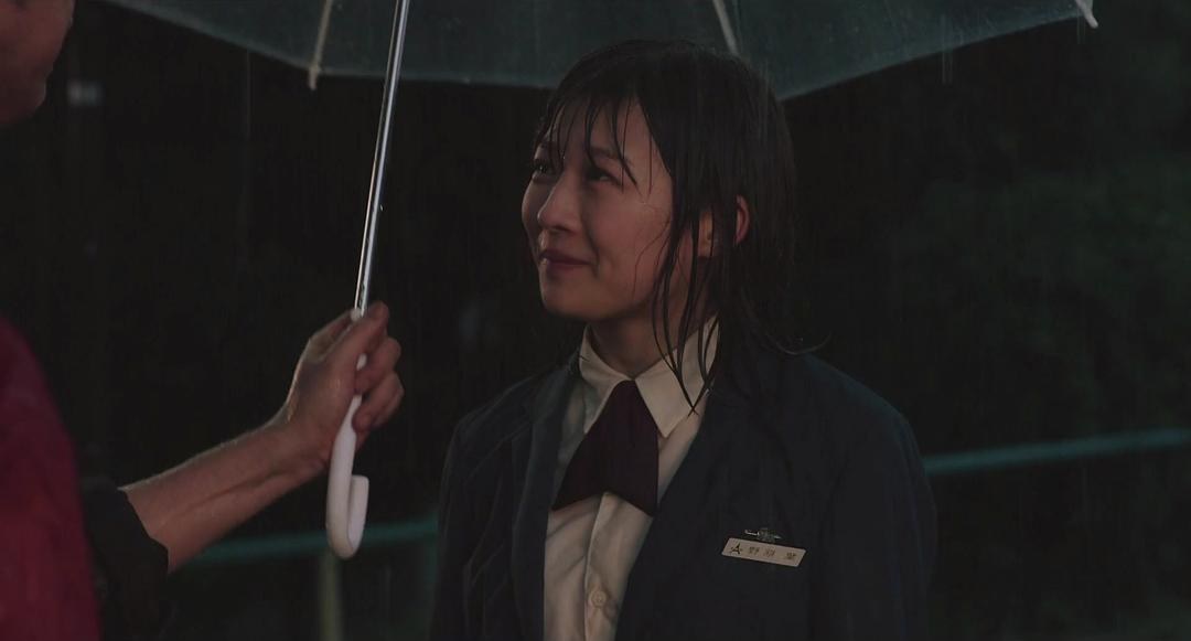 雨中穿深色制服的女子站在透明伞下微笑