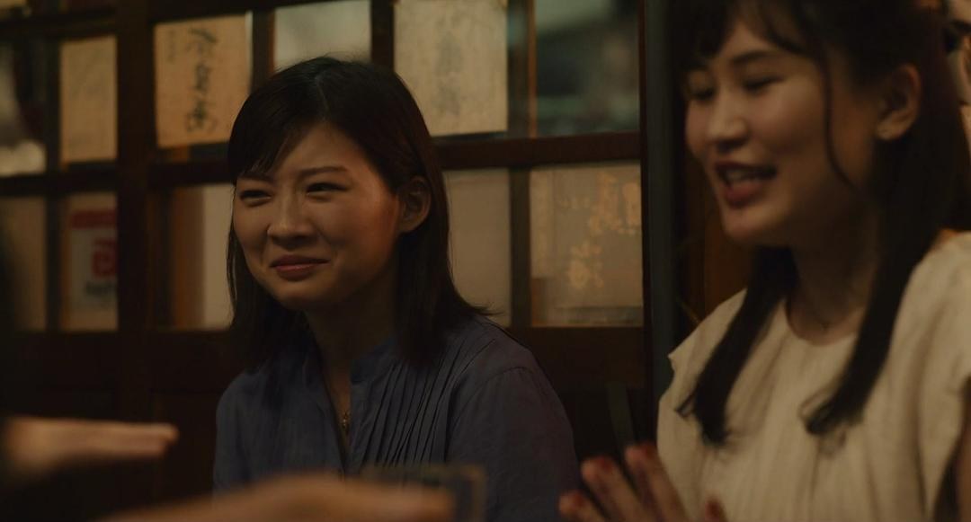 两名女子在餐桌边交谈,其中一人微笑看向前方