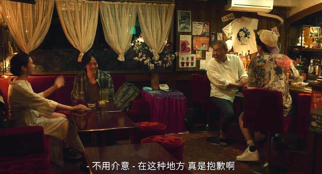 数名男女在昏暗酒吧内围坐,一名白发男子站在吧台旁