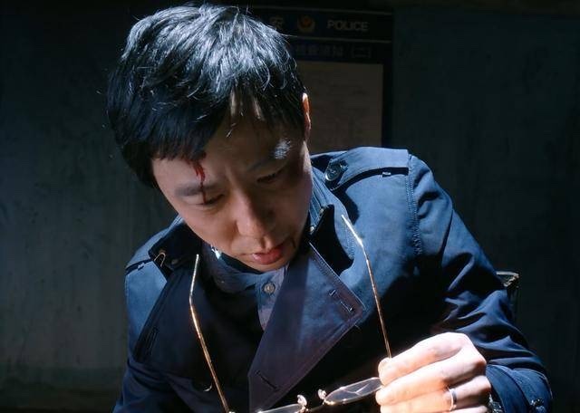 额头受伤的男子低头抓着眼镜