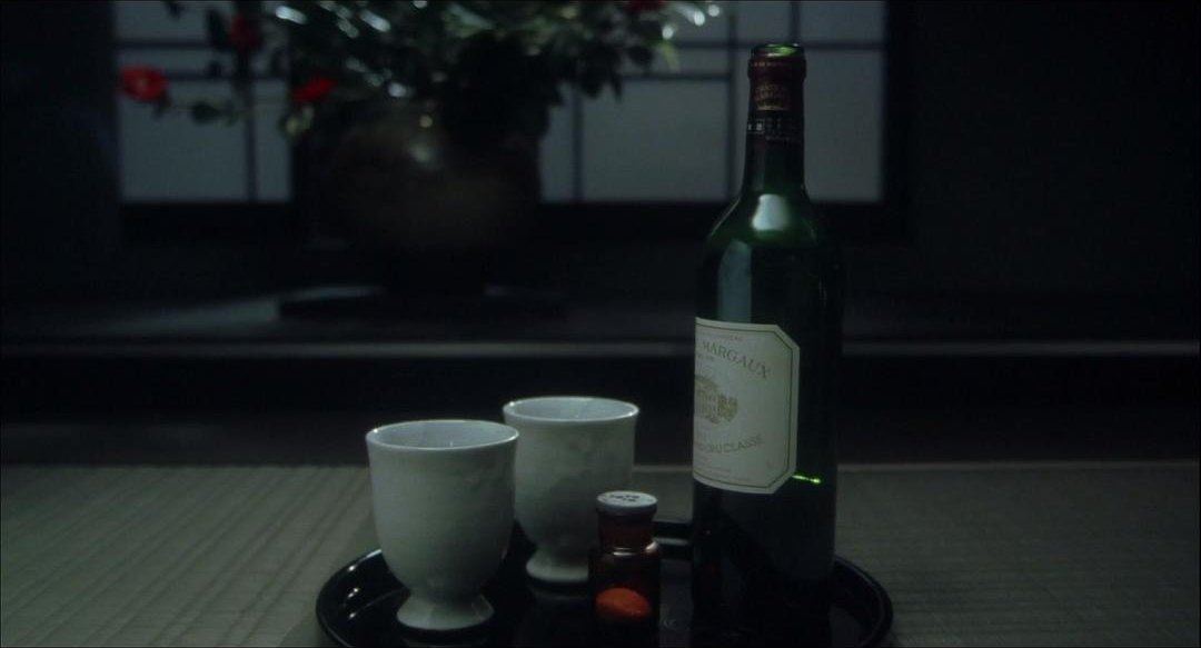 托盘上放着一瓶红酒、两个白色杯子和一只小药瓶