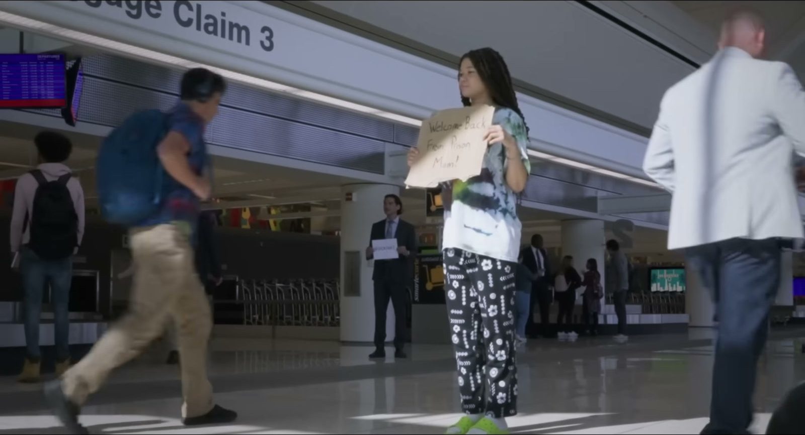 一名年轻女子举着接机牌站在机场到达大厅