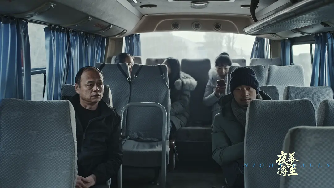 梁哲坐在回乡的中巴车后排,对面是一同回乡的同乡们