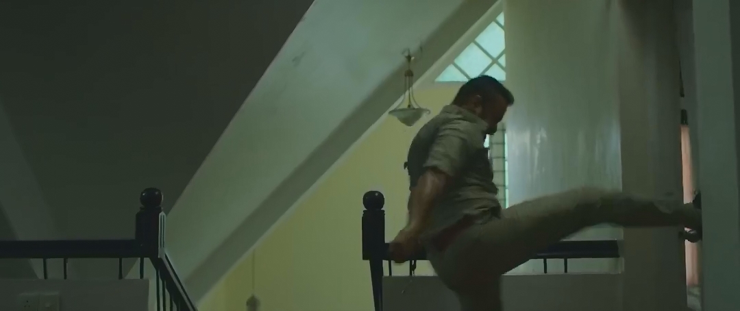 穿警服的男子抬腿踢向楼梯转角的门