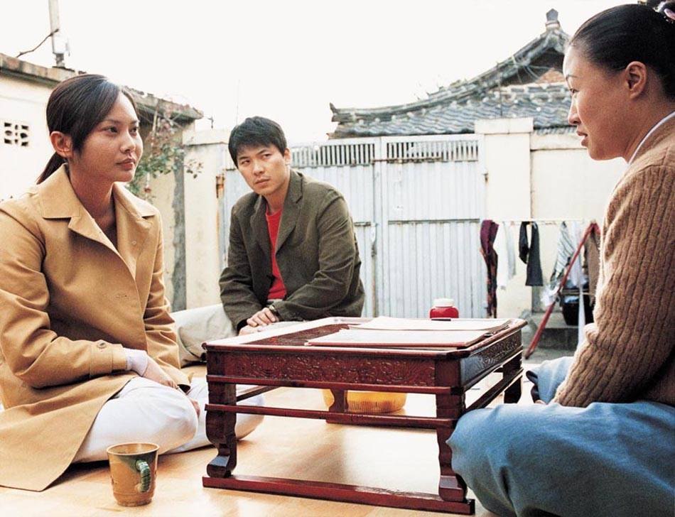 善英、庆洙与一名年长女子围坐在院中矮桌旁