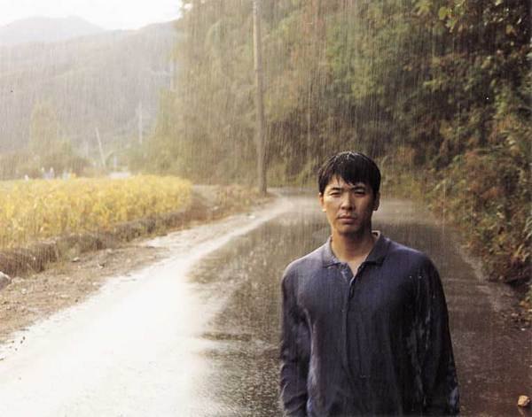 庆洙独自站在雨中的小路上