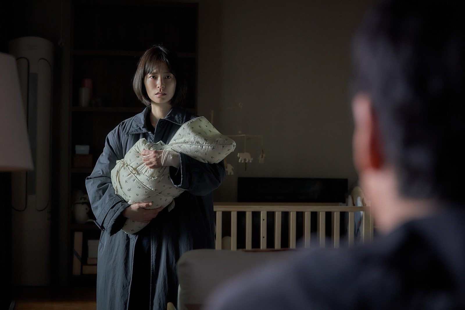 抱着婴儿的女人站在房间里望向前方