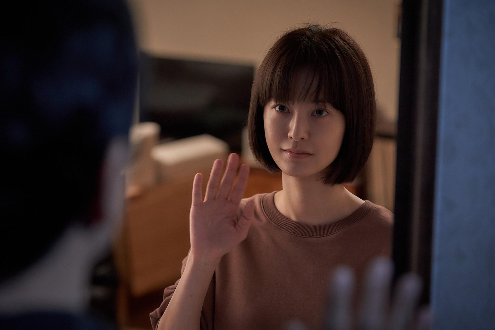 女人隔着玻璃举起一只手