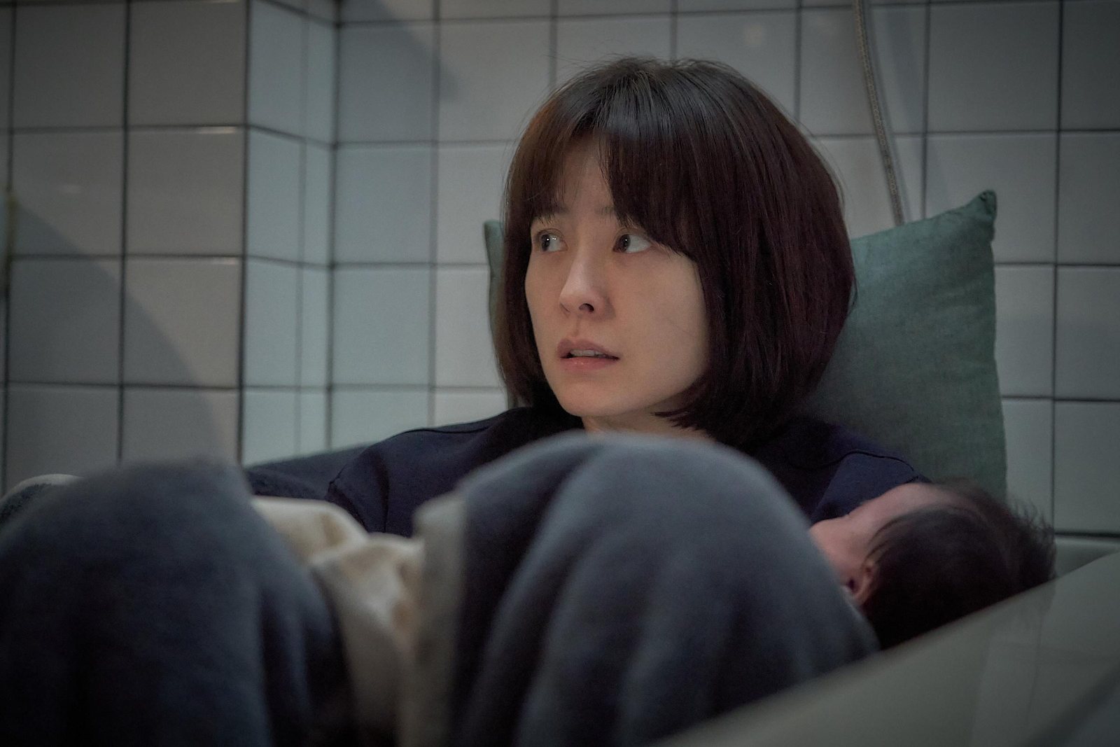 女人蜷坐在墙边抱着婴儿