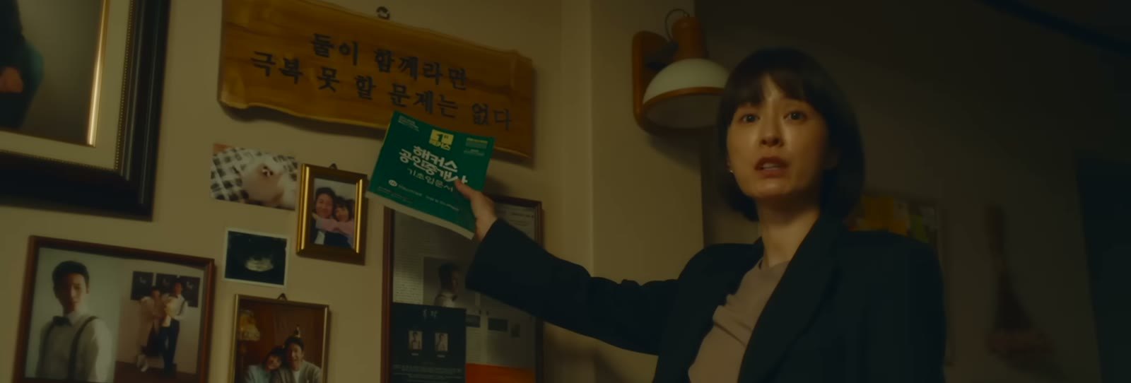 一名女子在照片墙前举起绿色物件
