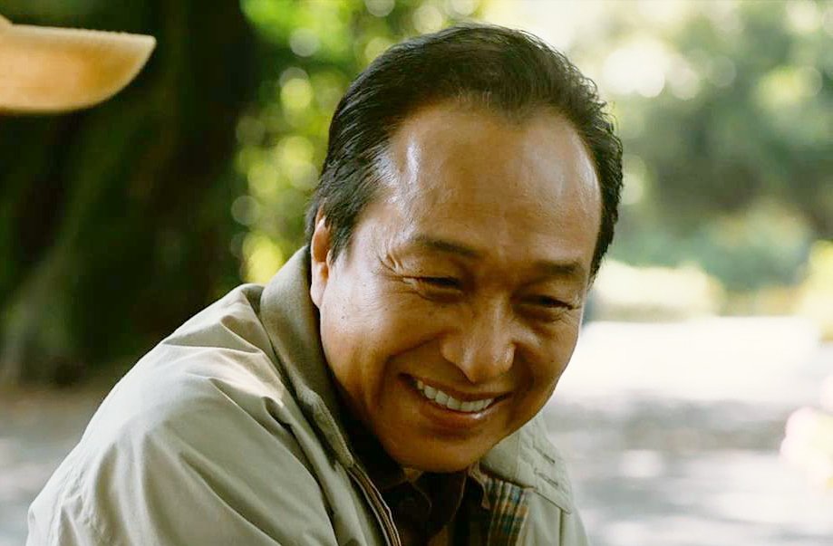 一名年长男子在户外笑着低头