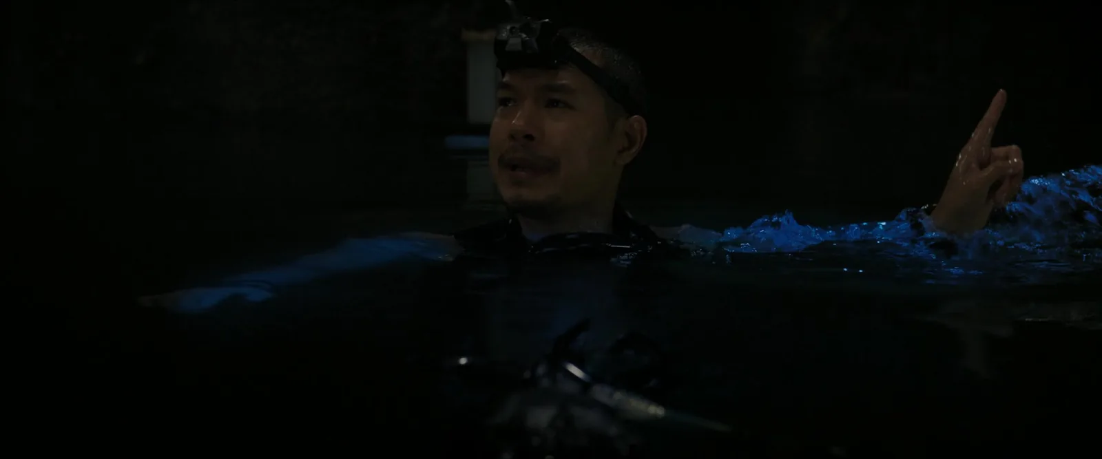 向导 Wat 戴着头灯浮在洞穴水面