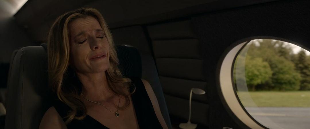 穿黑色上衣的女子闭眼坐在私人飞机的舷窗旁
