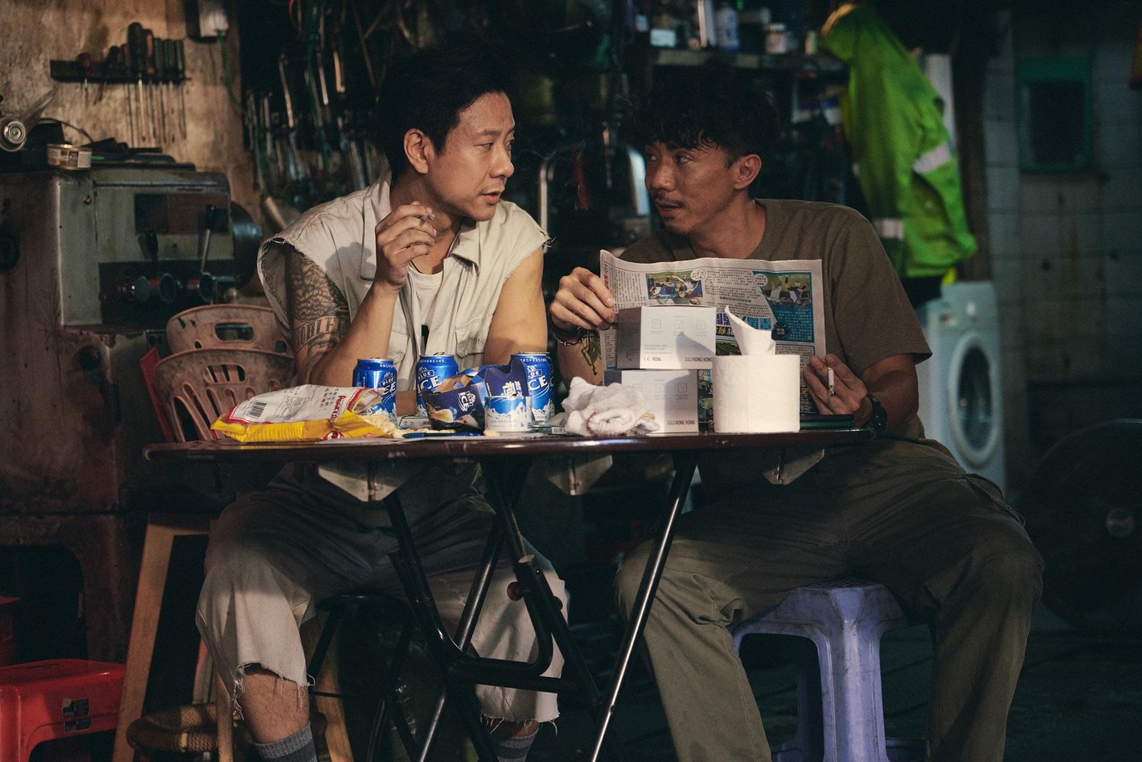 两名男子坐在车房的折叠桌旁交谈