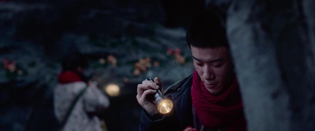 系红围巾的男子低头查看手中的手电