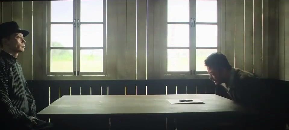 戴黑帽的男子与另一名男子隔着长桌相对而坐