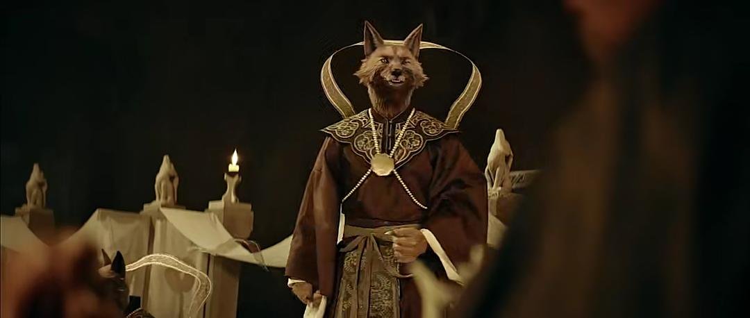 长着狐首、身穿礼服的身影站在堂会座席前