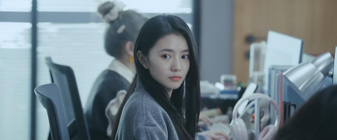一名女子坐在办公室工位前回头