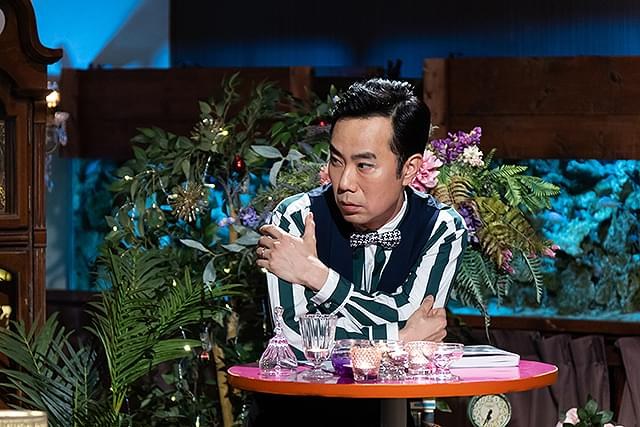 一名西装男子站在色彩鲜艳的演播室布景中