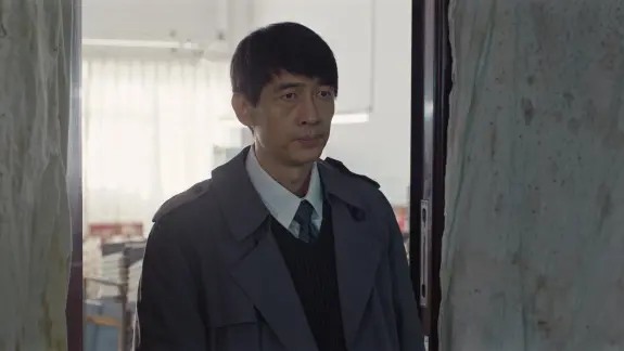 穿灰色外套的男子站在办公室门口