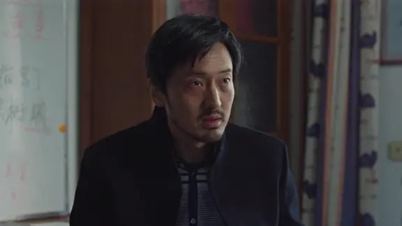 留胡须的男子站在门边