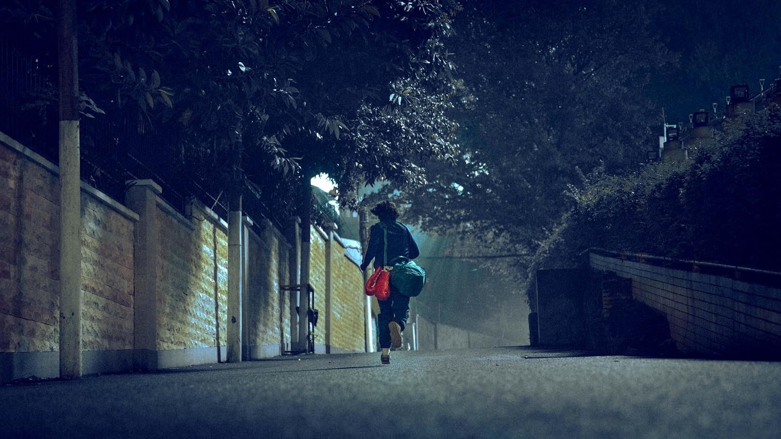 乐莹提着红色拳套和训练包走过夜间小巷