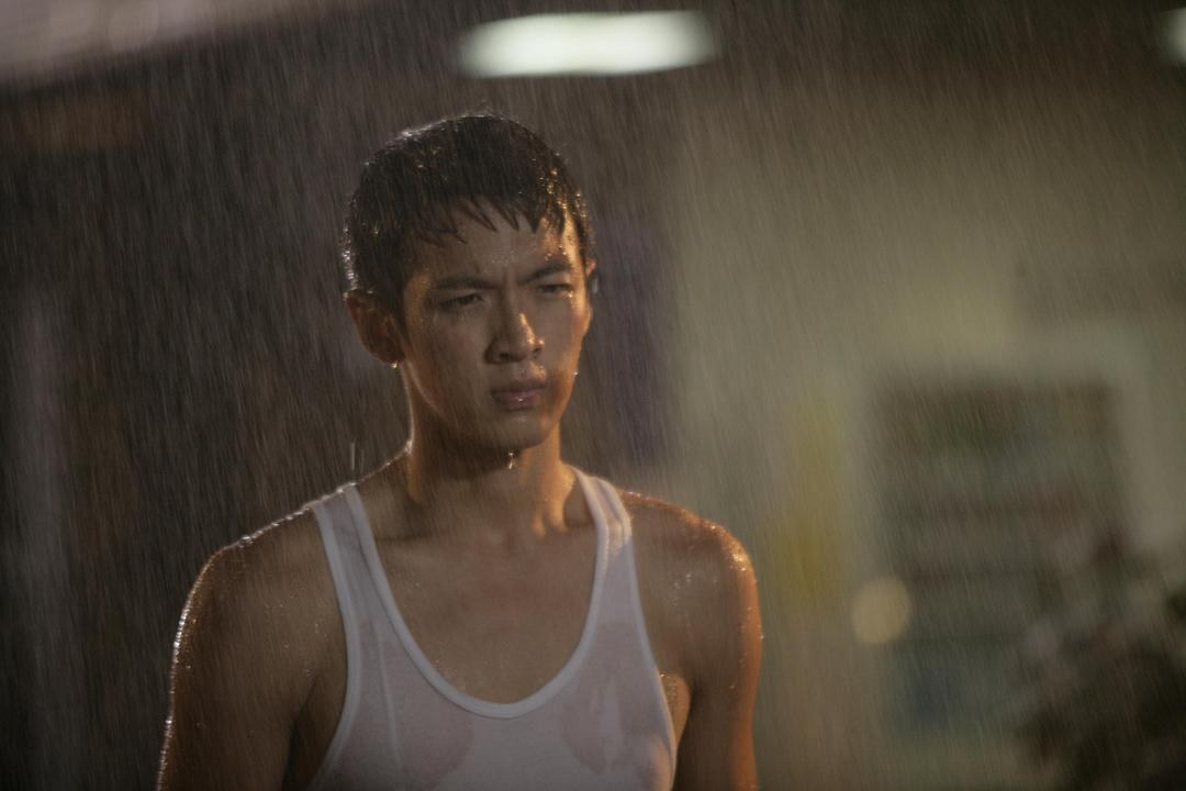 穿白色背心的男子站在大雨中